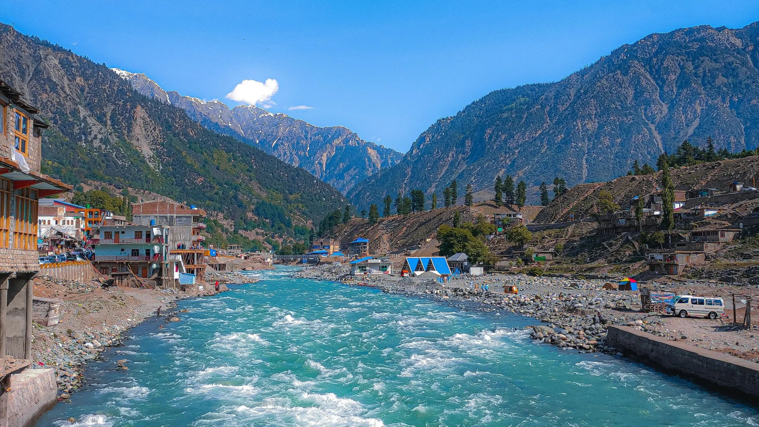 The turquoise Swat River rushing through Kalam between forested mountains and snow-capped peaks